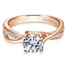 a rose gold engagement ring with diamonds on the band and a round cut diamond in the center