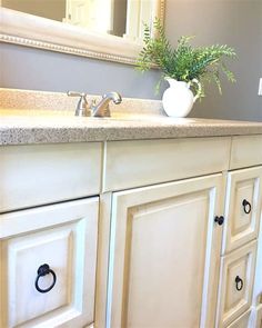 a bathroom vanity with white cabinets and a vase on top of the cabinet door,