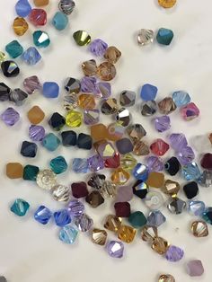 many different colored glass beads on a white surface