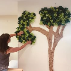 a woman is painting a tree on the wall