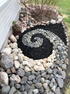 there is a rock garden with a spiral design in the center and black rocks around it