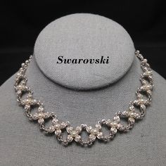 *Description: This is a great floral choker necklace by Swarovski with faux pearls and clear rhinestones on a rhodium plated backing from the 1990s. The links are flowers and the faux pearl is the center. The length is adjustable with an extension chain and lobster clasp. The end of the extension chain has a rhinestone swan which is the Swarovski logo. This would be a great addition to your vintage jewelry collection or make a great vintage gift! *Approximate Measurements: Length - 15 1/4 Inches Elegant Metal Rhinestone Necklace For Anniversary, Elegant Rhinestone Necklace For Anniversary, Silver Pearl Rhinestone Necklace For Formal Occasions, Formal Silver Rhinestone Necklace With Pearls, Formal Silver Pearl Rhinestone Necklace, Formal Silver Rhinestone Pearl Necklace, Silver Evening Choker Pearl Necklace, Silver Choker Pearl Necklace For Evening, Silver Pearl Choker For Evening