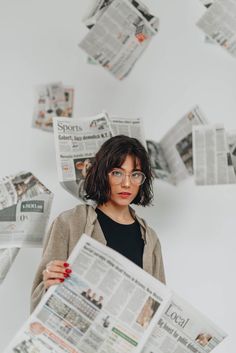 a woman with glasses holding up newspapers in front of her face