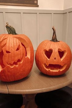 two carved pumpkins sitting on top of a table