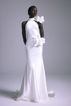 a woman in a white dress with flowers on her shoulder