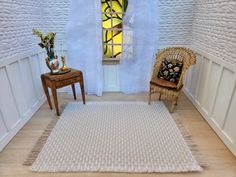 a room with a chair, table and rug on the floor in front of a stained glass window