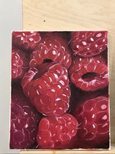 a painting of raspberries is shown on a easel next to a piece of wood