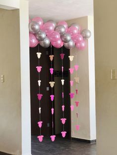 some pink and silver balloons are hanging from the ceiling in front of a door with mickey ears on it