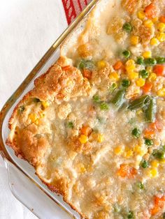 a casserole dish with vegetables and meat in it on a white table cloth