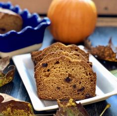 slices of pumpkin bread on a white plate with autumn leaves and an orange in the background