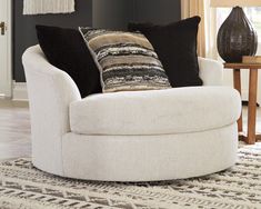 a white chair with black and brown pillows on it's back in a living room