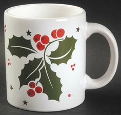 a white coffee mug with holly berries and stars on the rim, painted in red and green