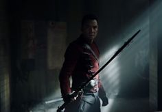 a man holding two swords in the dark