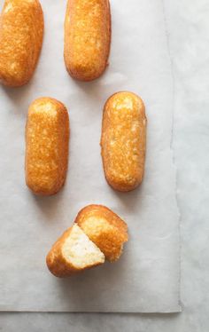 four doughnuts with one bite taken out and the other half eaten on a piece of parchment paper