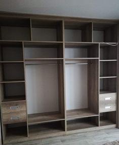 an empty room with wooden shelves and drawers