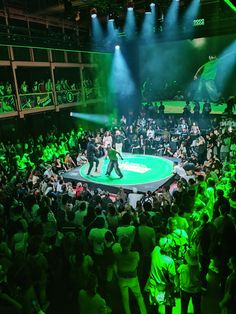 two men on stage in front of an audience at a sporting event with green lighting