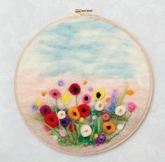 an embroidery project with colorful flowers on the front and behind it is a white background