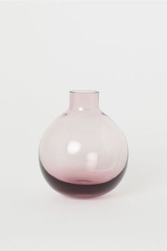 a pink glass vase sitting on top of a white table next to a black object