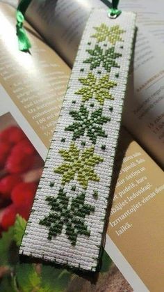 the bookmark is decorated with green and red flowers on it's side, along with an ornament