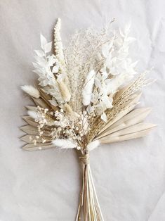 a bunch of dried flowers sitting on top of a white tablecloth covered floor next to an open book