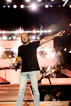 a man standing on top of a stage with his arms in the air and holding a microphone