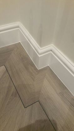 the corner of a room with wood flooring and white trim on the side wall