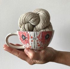 a hand holding a cup with yarn in it