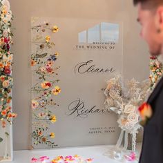 a man standing in front of a sign with flowers on it and confetti