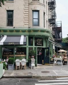 an outdoor cafe with tables and chairs on the sidewalk in front of a tall building