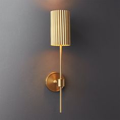 a gold wall light with a white shade on the side and a grey wall behind it