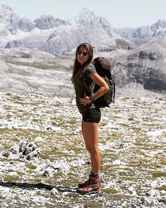 a woman standing on top of a snow covered field with a backpack in her hand