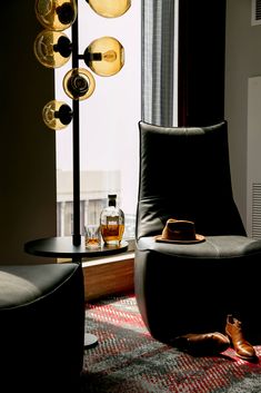 a living room with a chair, lamp and bottle on the floor next to a window