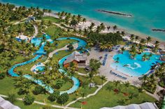 an aerial view of the resort with pool and water slides in the foreground, surrounded by palm trees