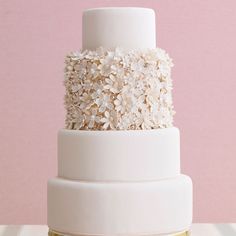 a three tiered cake with white flowers on top