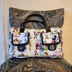 a mickey mouse purse sitting on top of a chair next to a wall with disney characters