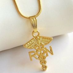 Gold Nursing Caduceus Necklace. Great Gift For The Graduate Rn Nurse. 16 To 18 Inch Long Chain. Nicely Detailed Rn Caduceus. Gold Plated Metal Alloy. Visit Our Store To See More Nursing & Medical Jewelry. Nurse Necklace, Purple Stone Necklace, Red Stone Necklace, Eagle Necklace, Medical Jewelry, Black Pearl Necklace, Nurse Graduation, Nurse Graduation Gift, The Graduate