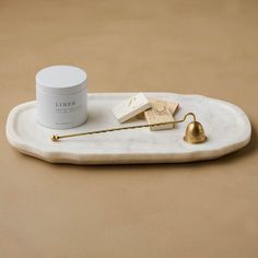 a white marble tray with a gold handle and some items on it, including a cream jar