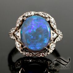 A beautiful opal halo ring with a bespoke, design for this cool/winter colored opal. Size 7 Solid 14k white gold Natural White Diamonds, SI-1, GH 5.07carat natural solid Australian semi-black crystal opal. 12.9 x 10.9 x 4.3mm This opal is not a full black, it is about an N3 with a semi transparency. Mined from Lightning Ridge, Australia. About a 3.5 Brightness Main colors are blue and green with subtle purples and the occasional fleck of magenta. the camera seems to home in on the magenta and blue, while in reality, the magenta is hard to see and the green, teal and blue are much more prominent. In order to see the opal in its true colors, see the video. I labeled two of the photos with the type of light. This is not a super strongly colored opal in indoor light, but really comes alive any Luxury Blue Opal Ring With Accent Stones, Luxury Blue Opal Ring With Gemstone, Luxury Sterling Silver Opal Ring With Gemstone Accents, Luxury Black Opal Ring, Elegant Style, Vintage Opal Engagement Ring, Blue Opal Ring In Sterling Silver, Spiritual Style, Hinged Ring, Cool Winter, Opal Band