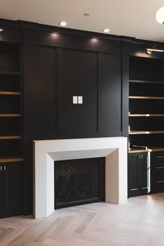 an empty living room with black bookcases and a fire place in the center