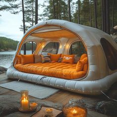 an inflatable bed is set up on the ground next to a lake with candles