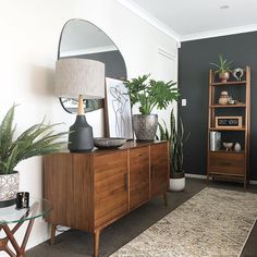 a living room filled with lots of furniture and plants on top of a wooden cabinet