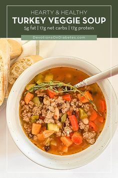 a white bowl filled with turkey veggie soup next to a baguette