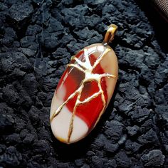 "Welcome to APRAZITA Discover our unique Kintsugi-Inspired Gemstone Jewelry Collection. Kintsugi is a revered Japanese art of mending broken pottery with gold-infused lacquer, transforming flaws into beautiful, valuable features. At APRAZITA, we apply this same process to repair gemstones, infusing them with renewed beauty and significance. Modern kintsugi repairs each gemstone with epoxy paste and gold leaf, symbolizing the beauty in healing life's broken places. Each kintsugi-repaired gemstone is one-of-a-kind due to the process's randomness. The pictured jewelry is the one you'll receive. Take a closer look at each image to fully appreciate the distinctive intricacies of this remarkable gemstone. Our dedication to merging gemstones with other art forms is truly exceptional. 🔹 ITEM DETA Elegant Necklace With Artistic Round Pendant, Minimalist Glass Jewelry For Gifts, Handmade Glass Pendant Jewelry, Glass Jewelry With Natural Stones For Gift, Elegant Jewelry With Artistic Round Pendant, Handmade Red Oval Necklace, Minimalist Glass Jewelry Perfect For Gifts, Oval Amber Necklace For Gift, Artisan Necklace With Round Pendant For Gift