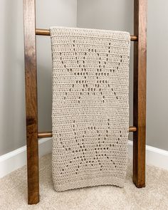 a white crocheted blanket sitting on top of a wooden chair next to a wall