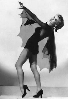 a black and white photo of a woman wearing a bat costume