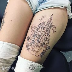 a woman's thigh with a castle tattoo on her left leg and stars in the background