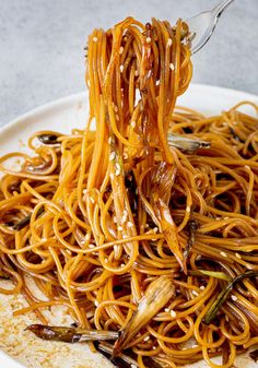 a fork full of noodles on a white plate