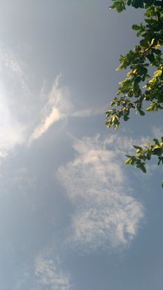 an airplane is flying in the sky with some clouds and trees around it on a sunny day