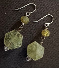 These earrings feature prehnite and green garnet stones set in sterling silver. They hang at a length of 1 1/4 inches. The combination of the light green prehnite and the deep green garnet creates a beautiful and unique look. These earrings would make a lovely addition to any jewelry collection. Sterling Silver Earrings With Natural Stones For May Birthstone, Sterling Silver Earrings With May Birthstone, Green Sterling Silver Gemstones For Jewelry Making, Green Amethyst Jewelry With Natural Stones, Handmade Silver Jewelry With Green Amethyst, Sterling Silver Faceted Earrings For May Birthstone, Green Spiritual Earrings For Healing, Spiritual Green Earrings With Natural Stones, Green Jade Earrings For Healing