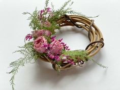 a wicker wreath with pink flowers and greenery